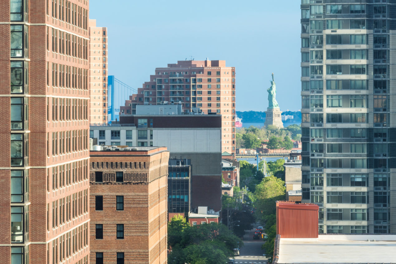 view of statue of liberty through downtown jersey city