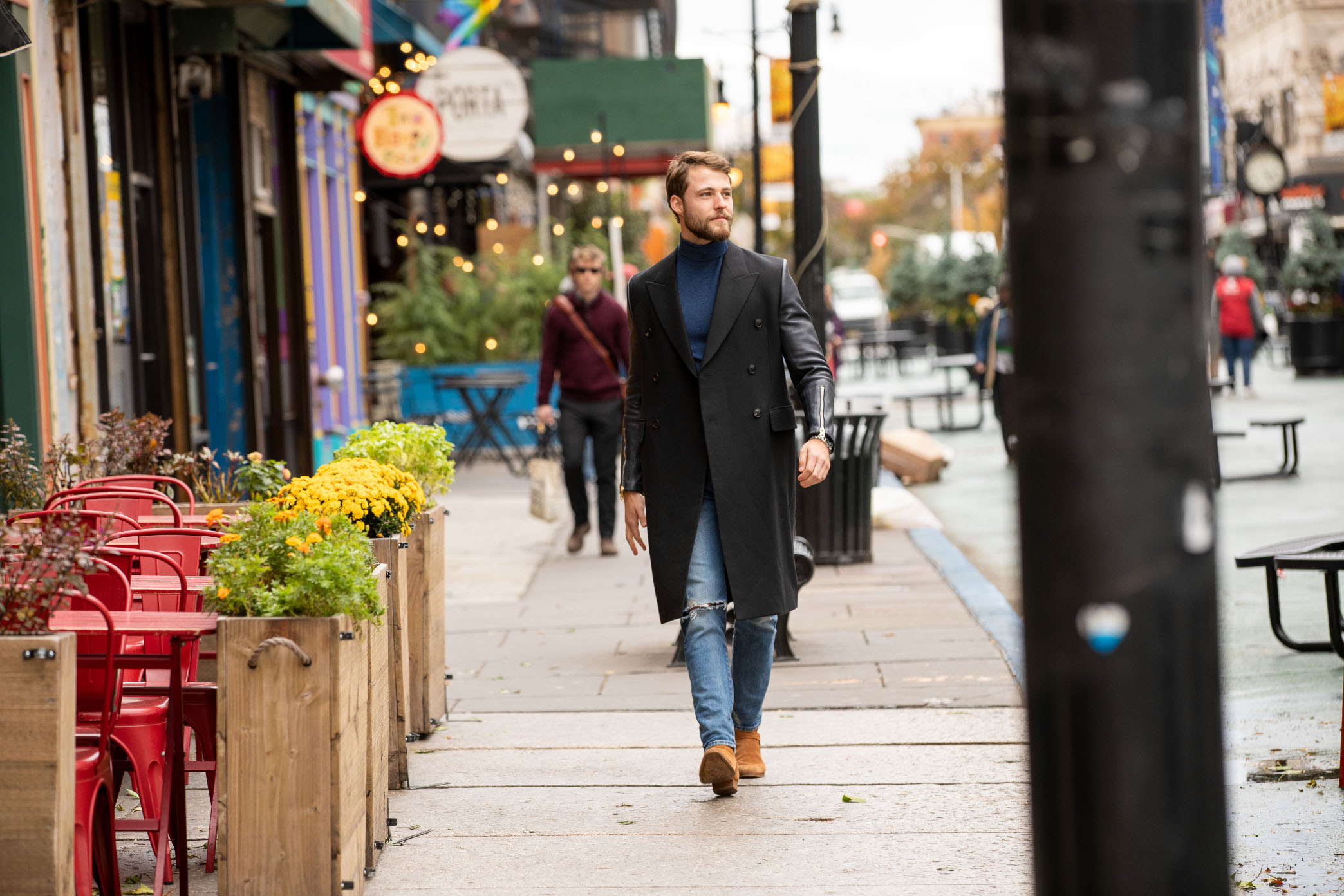 man in black coat walking down newark ave in jersey city by porta and two boots