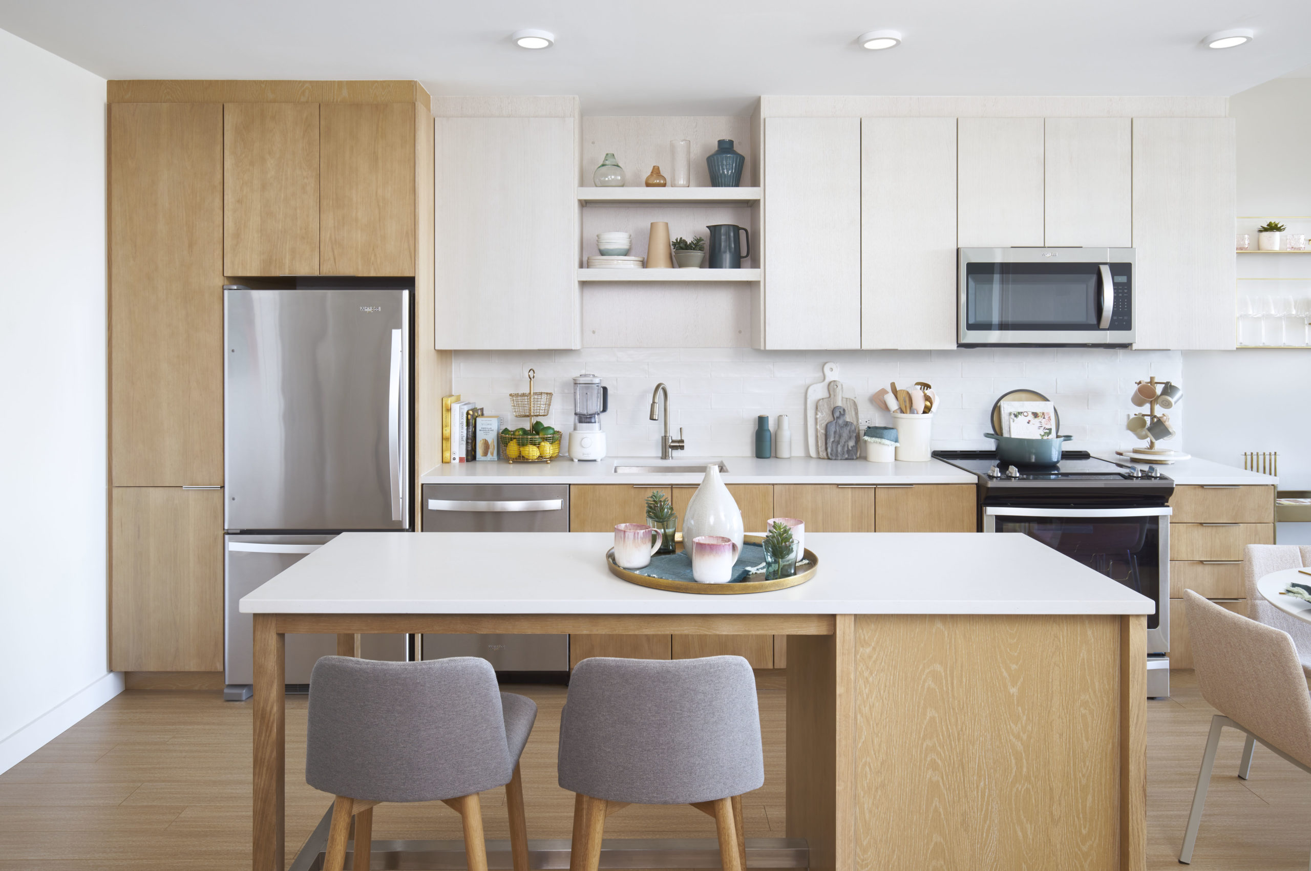 open kitchen and dining area island with light wood finishes and stainless steel