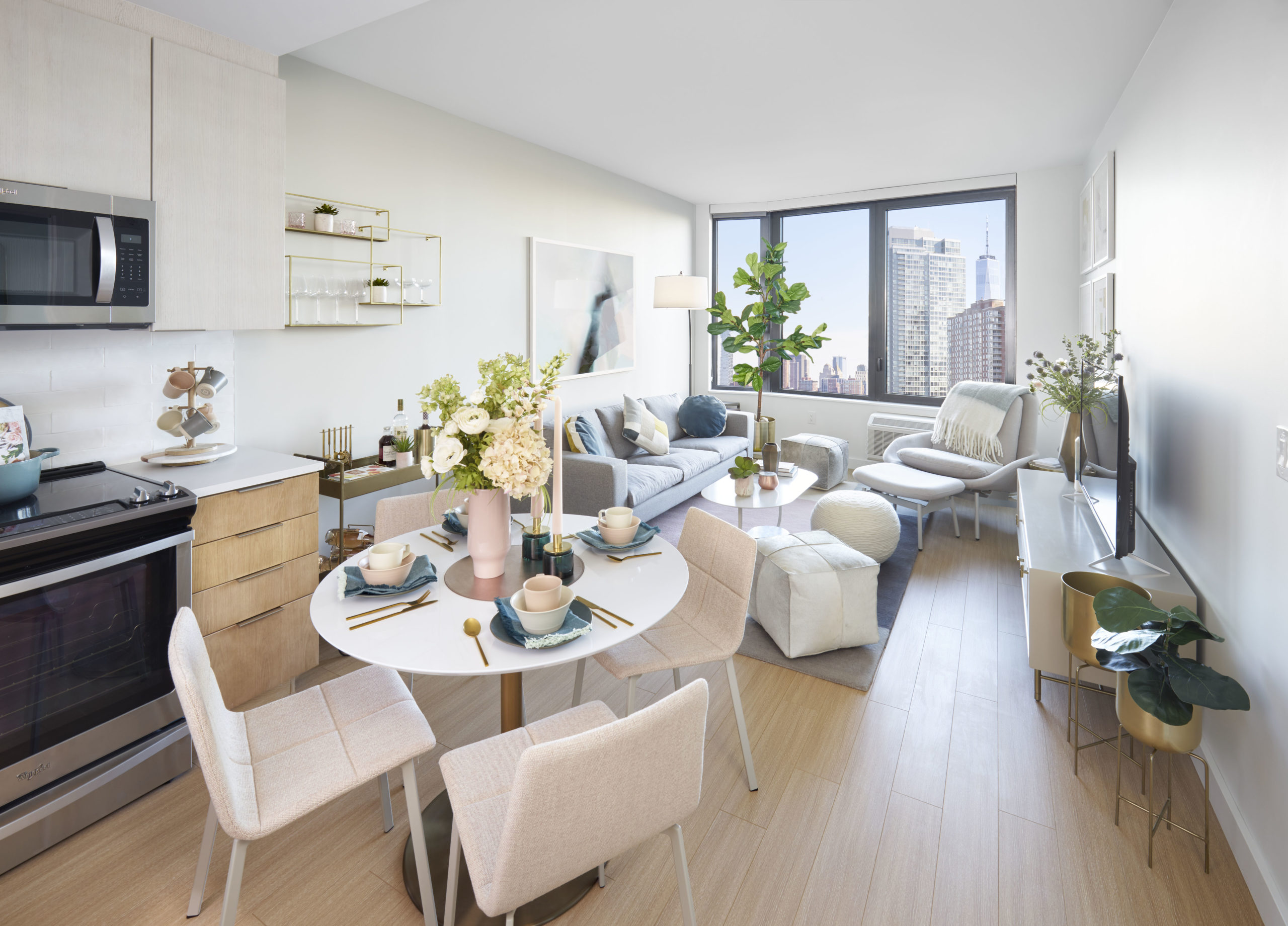 open dining and living room with circle table and wall to wall windows overllooking nyc