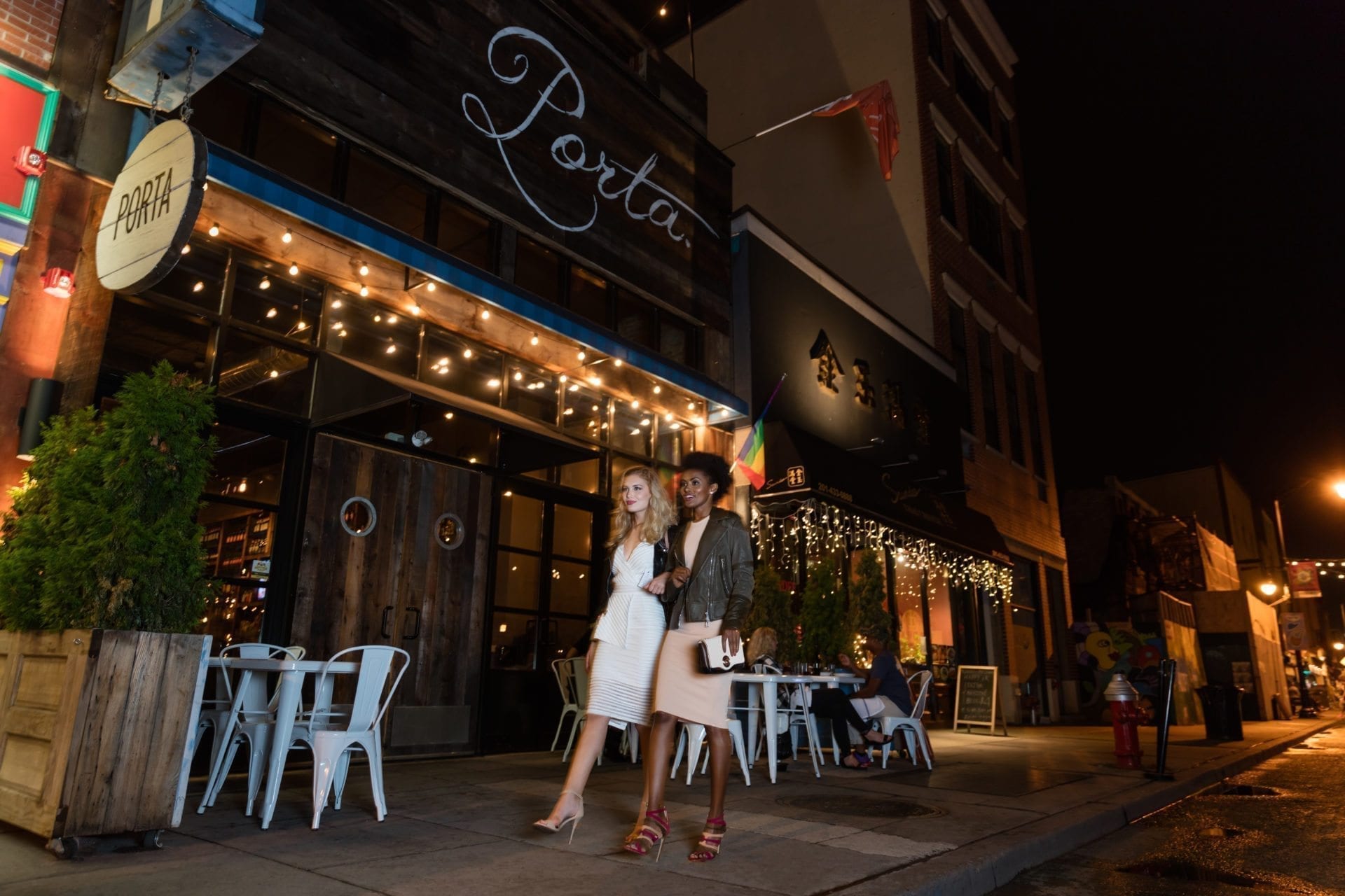 friends walking through night past porta pizza in jersey city