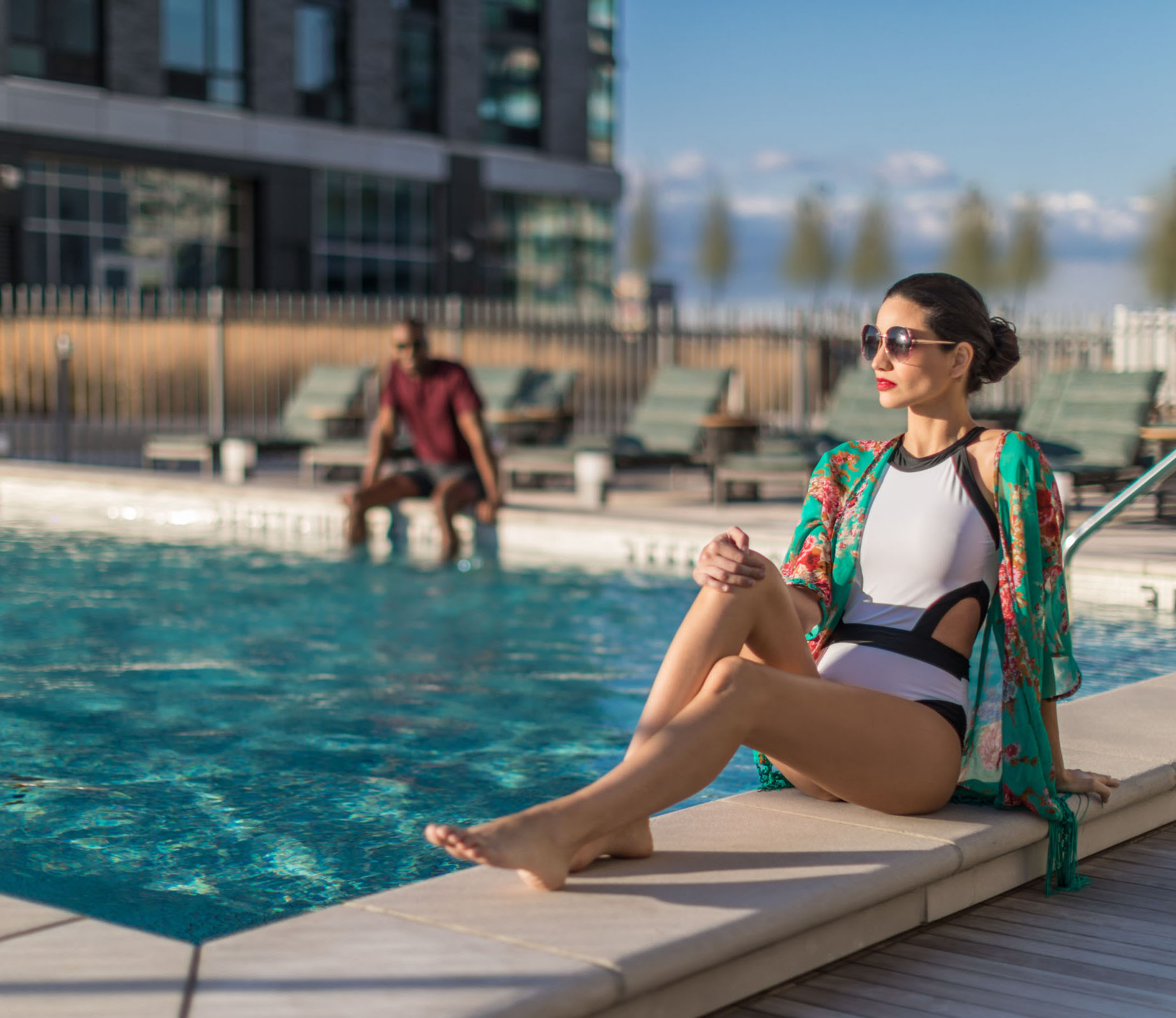 woman-sitting-pool-edge-resize woman sitting pool side with friend sitting in pool